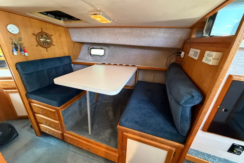 Slide: The Image of 1987 Silverton 34 Convertible interior with cozy dining area and blue cushioned seating. - 22