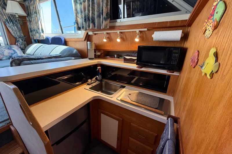 Slide: The Image of 1987 Silverton 34 Convertible boat interior kitchen with microwave, sink, and wooden cabinetry. - 25
