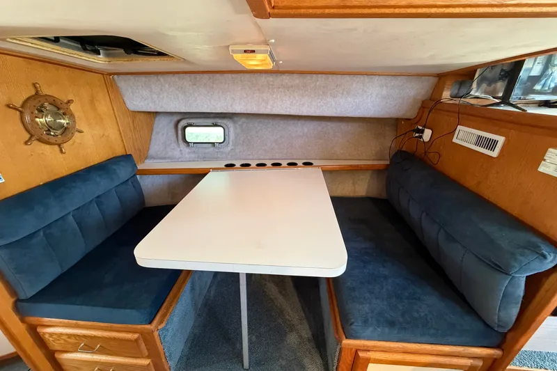 Slide: The Image of 1987 Silverton 34 Convertible interior with blue cushioned seating and a white table. - 23
