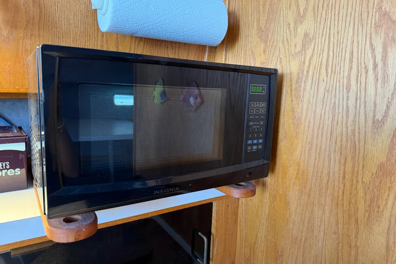 Slide: The Image of Microwave inside 1987 Silverton 34 Convertible boat kitchen, with wooden cabinetry and paper towel holder. - 28