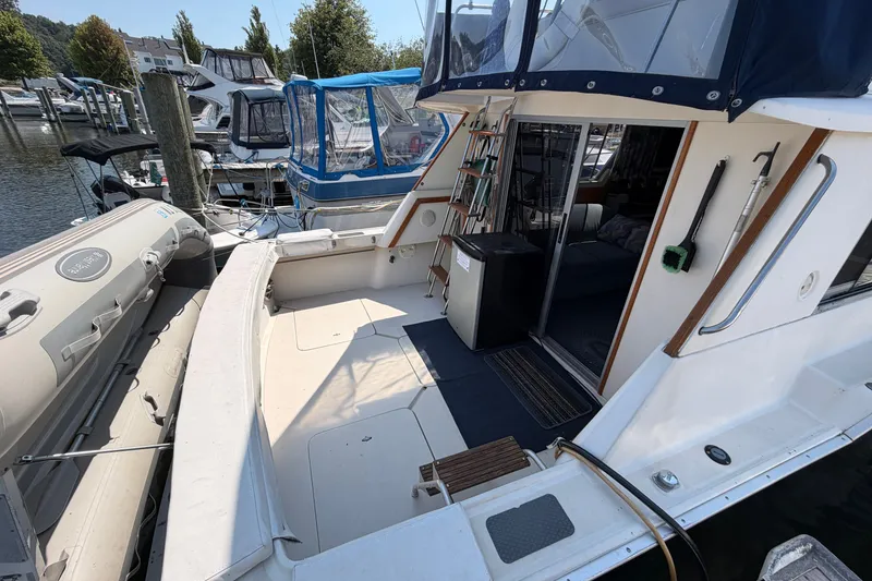 Slide: The Image of 1987 Silverton 34 Convertible yacht docked, featuring spacious deck and inflatable dinghy. - 7