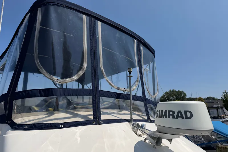 Slide: The Image of 1987 Silverton 34 Convertible boat with Simrad radar, featuring clear enclosure under blue sky. - 2