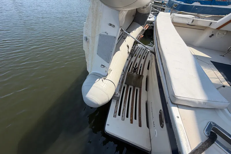 Slide: The Image of 1987 Silverton 34 Convertible boat with inflatable dinghy, docked on calm water. - 6