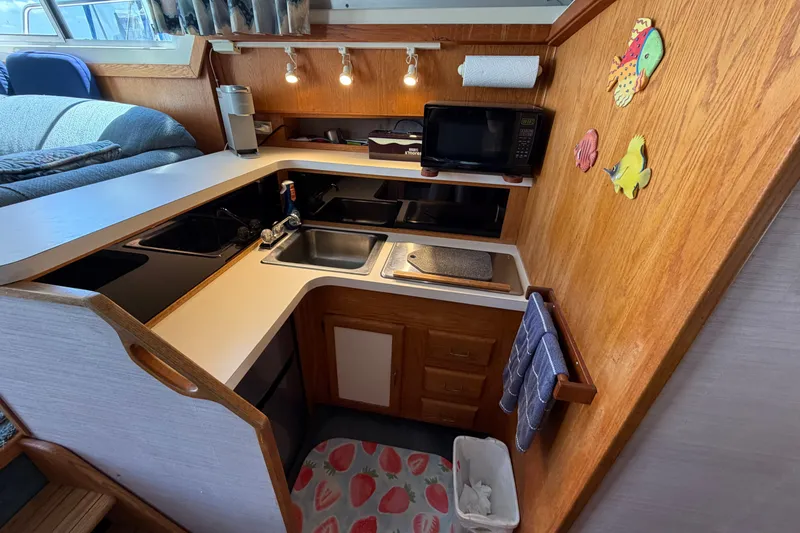 Slide: The Image of 1987 Silverton 34 Convertible boat kitchen with sink, microwave, and wooden cabinetry. - 24
