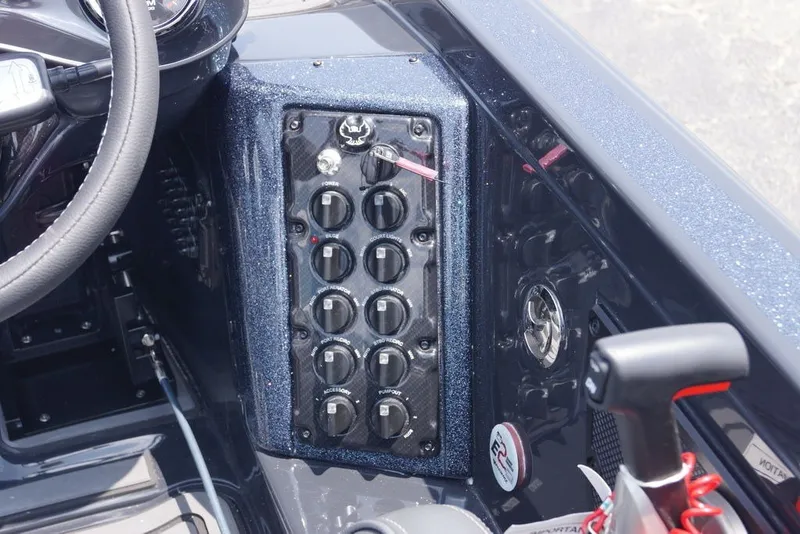 Slide: The Image of Dashboard controls of a 2027 Phoenix 921 Elite X boat, featuring multiple switches and steering wheel. - 15