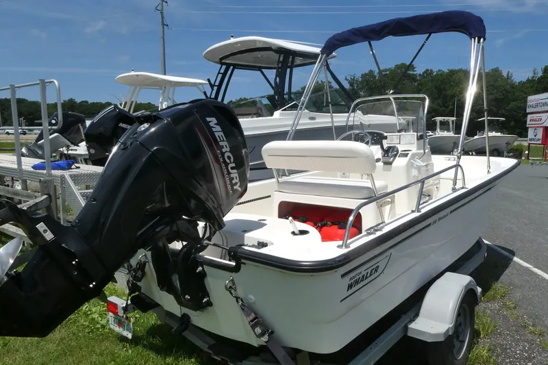 Slide: The Image of 2011 Boston Whaler 150 Montauk boat with Mercury engine on trailer, parked outdoors. - 2