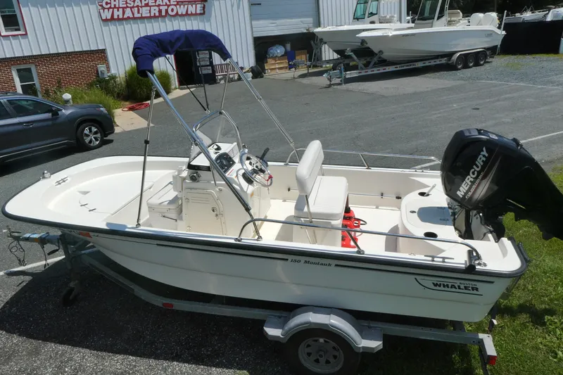 Slide: The Image of 2011 Boston Whaler 150 Montauk boat on trailer with Mercury engine, parked outdoors. - 3