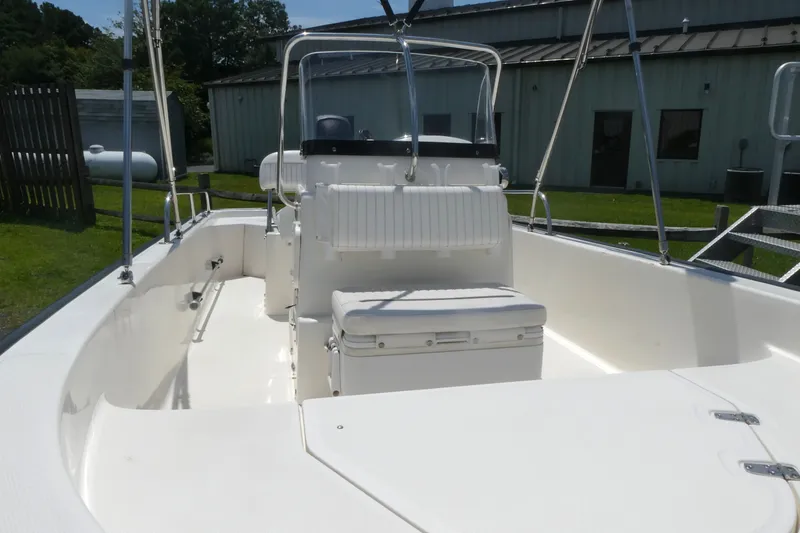 Slide: The Image of 2011 Boston Whaler 150 Montauk boat interior with seating and console, docked outdoors. - 9