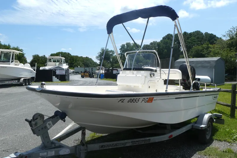 Slide: The Image of 2011 Boston Whaler 150 Montauk boat on trailer, parked outdoors under blue sky. - 1
