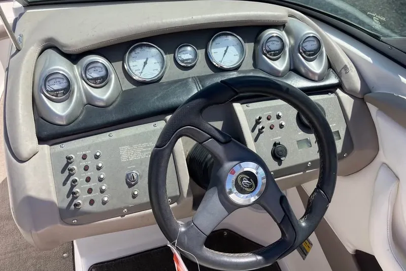Slide: The Image of Steering wheel and dashboard of a 2003 Cobalt 220 boat with gauges and controls. - 14