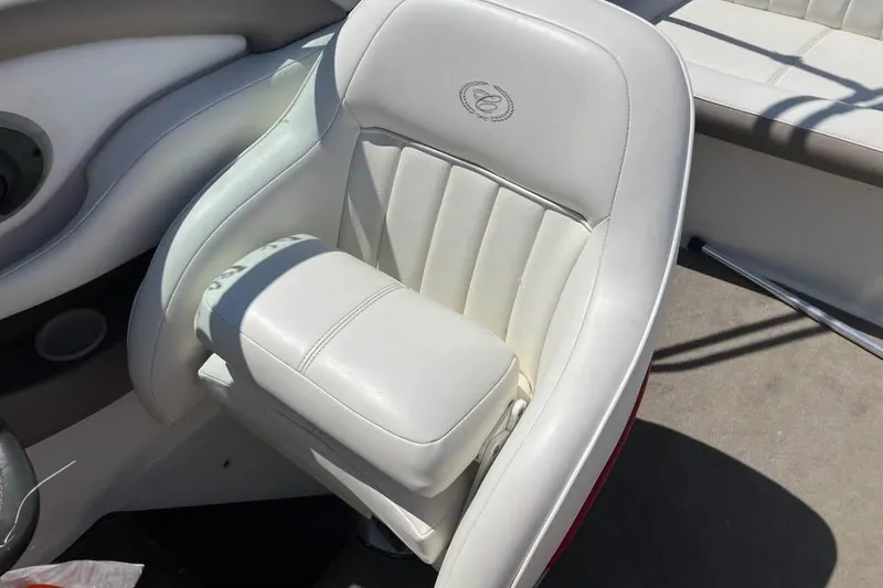 Slide: The Image of White leather seat in a 2003 Cobalt 220 boat, featuring elegant stitching and logo. - 16