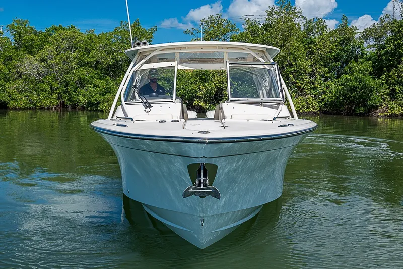 Slide: The Image of 2024 Grady-White Freedom 307 boat on calm water, surrounded by lush greenery. - 13