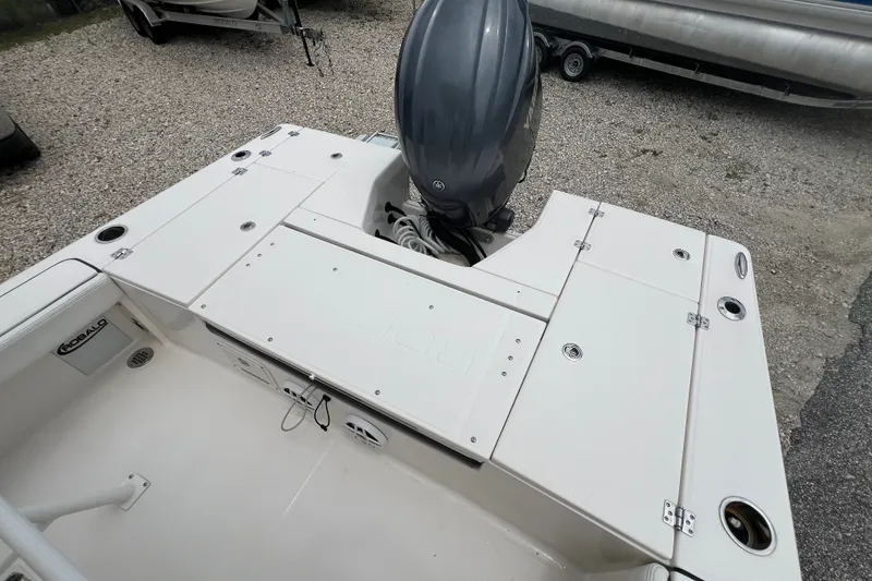 Slide: The Image of 2024 Robalo 226 Cayman boat deck with outboard motor, featuring storage compartments and rod holders. - 9