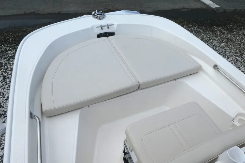 Slide: The Image of 2027 Boston Whaler 150 Montauk boat interior with cushioned seating and stainless steel railings. - 9
