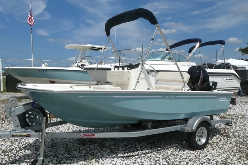 The Image of 2027 Boston Whaler 150 Montauk boat on trailer, displayed outdoors under blue sky. - 0