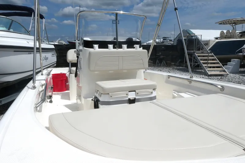 Slide: The Image of 2027 Boston Whaler 150 Montauk boat interior with seating and console, docked under blue sky. - 10