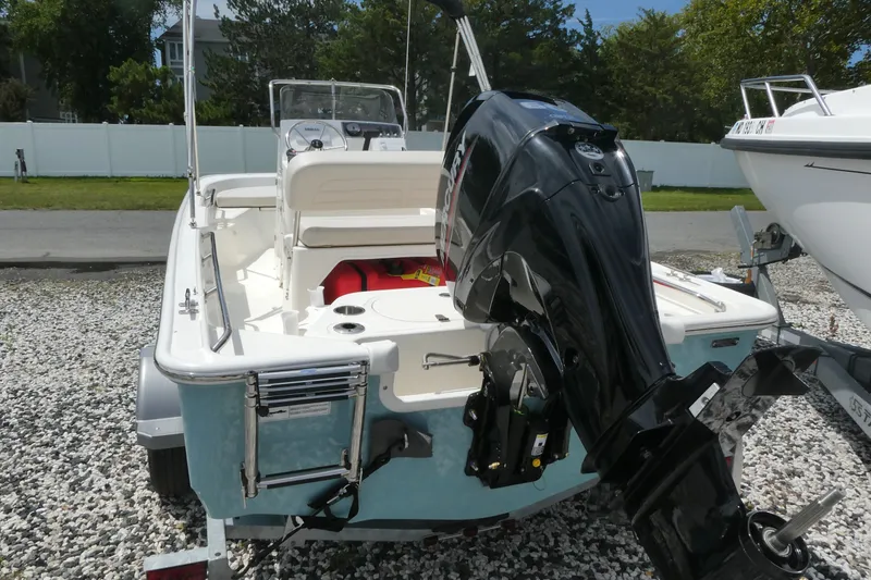 Slide: The Image of 2027 Boston Whaler 150 Montauk boat with outboard motor on gravel surface. - 2