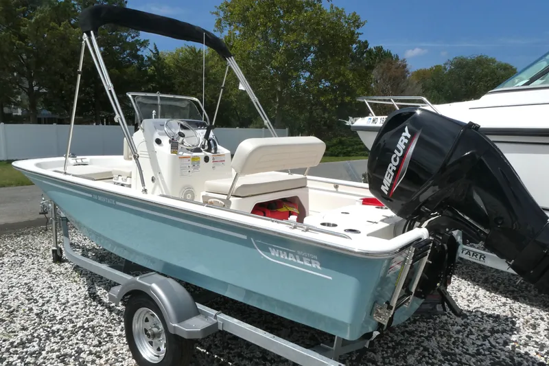 Slide: The Image of 2027 Boston Whaler 150 Montauk boat with Mercury engine on trailer, parked outdoors. - 1