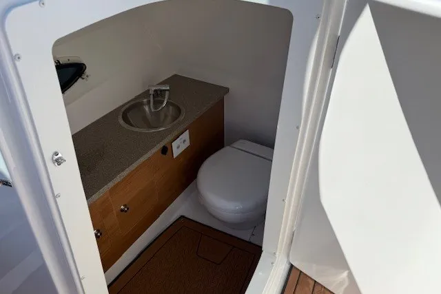 Slide: The Image of Interior of 2026 Hurricane SunDeck 2690 OB boat featuring a compact bathroom with sink and toilet. - 13