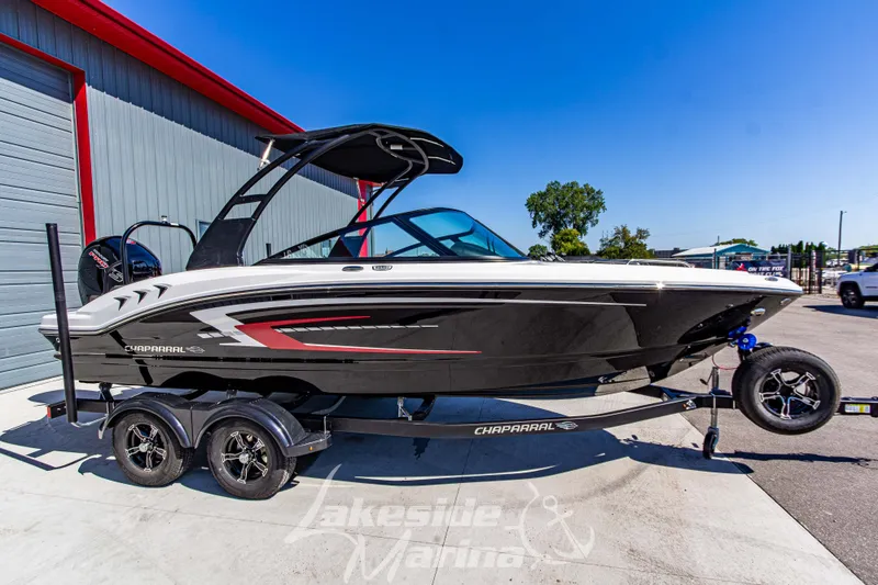 Slide: The Image of 2026 Chaparral 21 SSi OB boat on trailer, parked outdoors near a marina. - 3