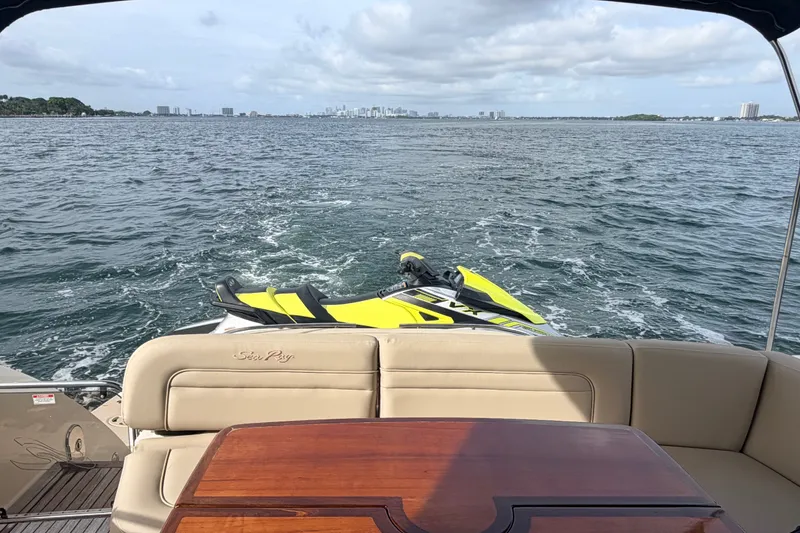 Slide: The Image of 2016 Sea Ray Sundancer 540 yacht with jet ski on open water, city skyline in background. - 50
