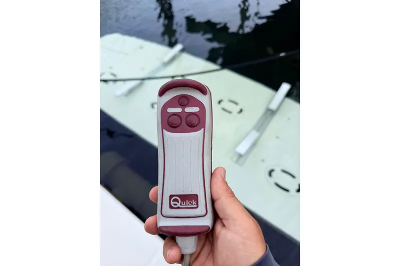 Slide: The Image of Hand holding a Quick remote control near a 2016 Sea Ray Sundancer 540 yacht. - 51