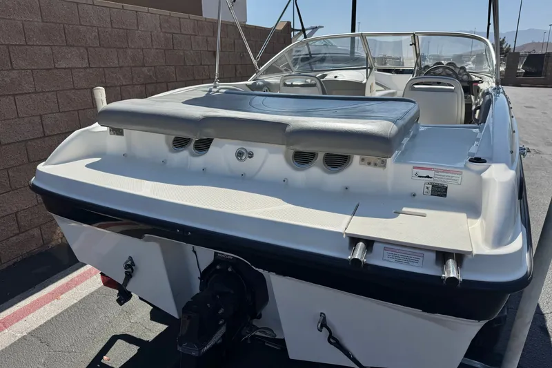 Slide: The Image of 2011 Bayliner 185 Bowrider boat, rear view, parked outdoors, showcasing seating and engine area. - 6