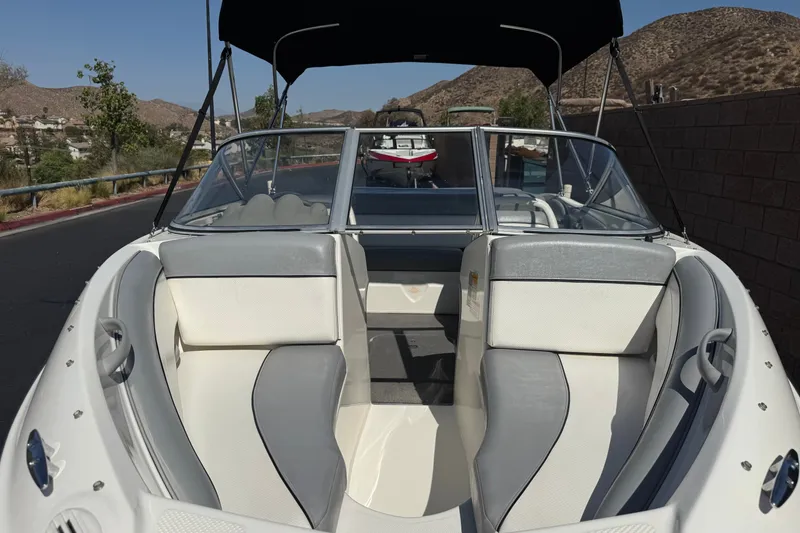 Slide: The Image of 2011 Bayliner 185 Bowrider boat with gray and white interior, parked on a sunny road. - 9