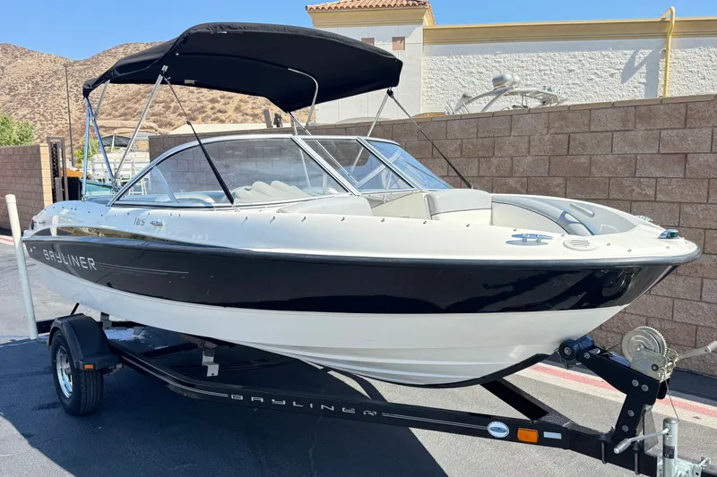 Slide: The Image of 2011 Bayliner 185 Bowrider boat on trailer, black and white exterior, parked outdoors. - 1