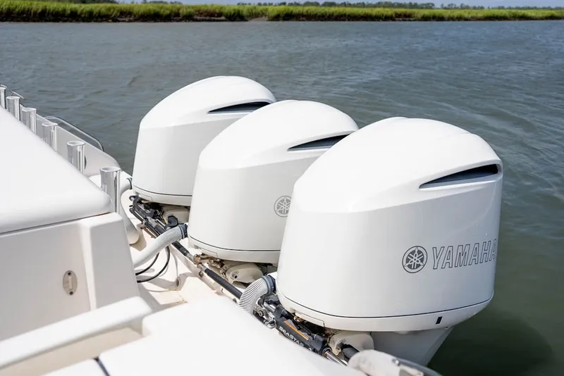 Slide: The Image of Triple Yamaha outboard engines on a 2015 Pursuit OS 385 Offshore boat in calm waters. - 9