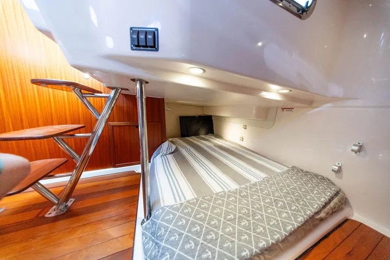 Slide: The Image of 2015 Pursuit OS 385 Offshore cabin interior with cozy bed and wooden steps. - 29