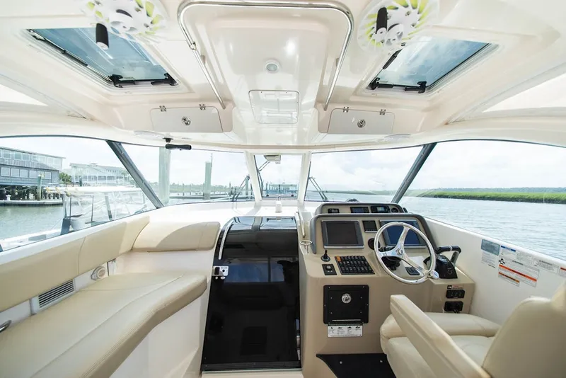 Slide: The Image of 2015 Pursuit OS 385 Offshore boat interior with helm and seating area. - 17