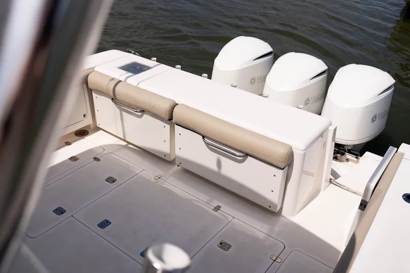 Slide: The Image of 2015 Pursuit OS 385 Offshore boat deck with cushioned seating and triple outboard engines. - 8
