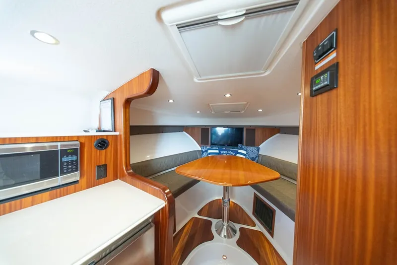 Slide: The Image of 2015 Pursuit OS 385 Offshore cabin interior with wood finish, table, and seating area. - 27