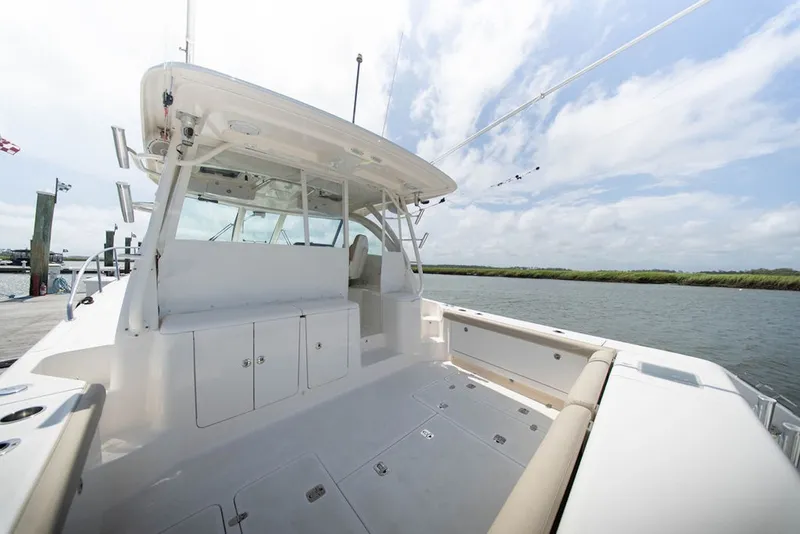 Slide: The Image of 2015 Pursuit OS 385 Offshore boat docked, showcasing spacious deck and seating area. - 14