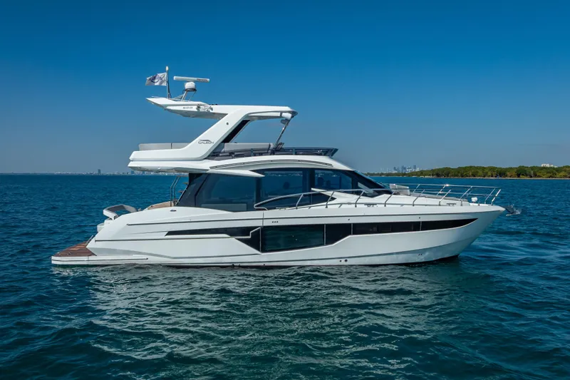 Slide: The Image of 2021 Galeon 500 Fly yacht cruising on open water under clear blue skies. - 16