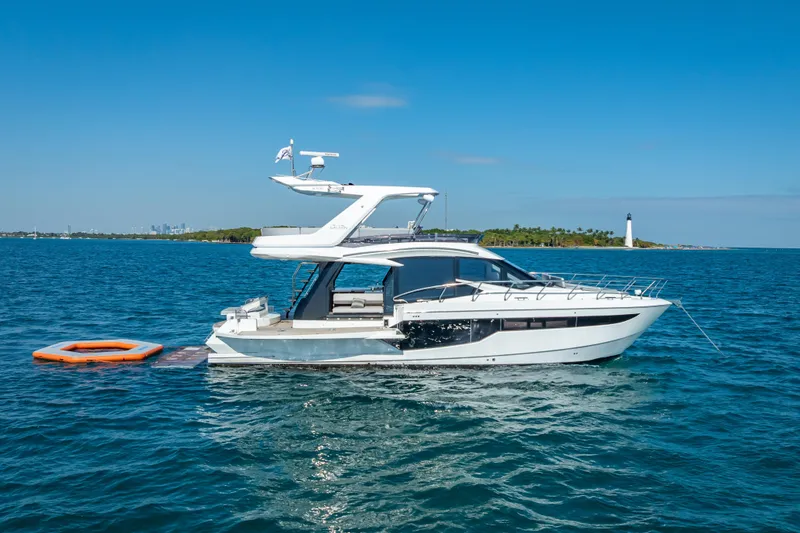 Slide: The Image of 2021 Galeon 500 Fly yacht anchored in serene blue waters near a lighthouse. - 61