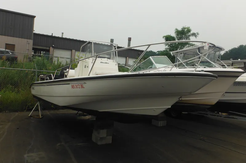 The Image of 2003 Boston Whaler 220 Dauntless boat on blocks in a storage yard. - 0