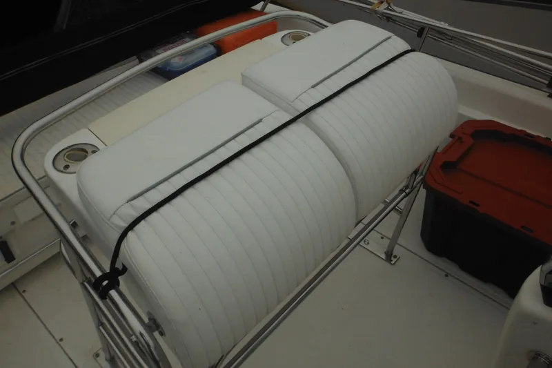 Slide: The Image of 2003 Boston Whaler 220 Dauntless boat interior with cushioned seating and storage compartments. - 17