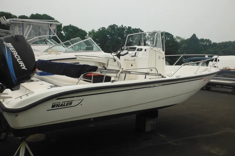 Slide: The Image of 2003 Boston Whaler 220 Dauntless boat with Mercury engine, docked outdoors. - 15