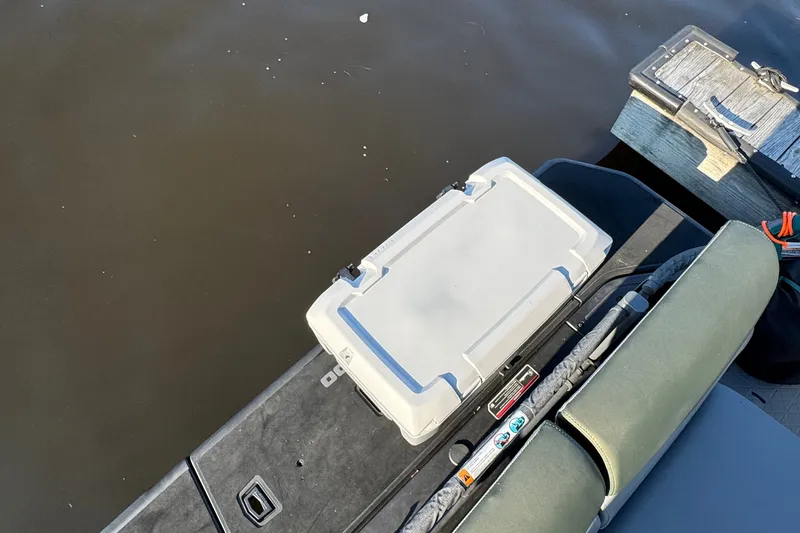 Slide: The Image of 2025 Sea-Doo Switch Fish 21 deck with storage box and seating, docked by water. - 11
