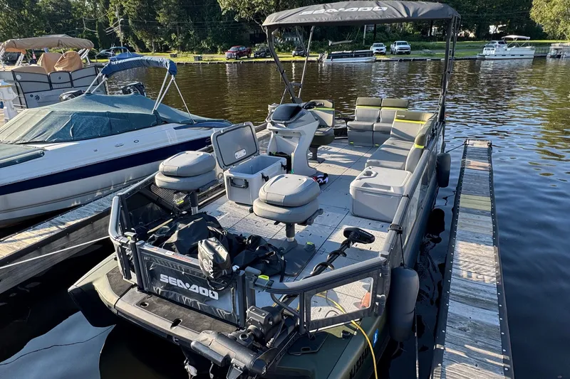 Slide: The Image of 2025 Sea-Doo Switch Fish 21 pontoon boat docked on a calm lake. - 1