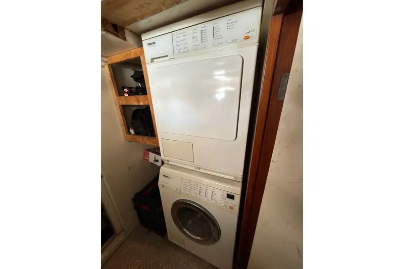 Slide: The Image of Stacked washer and dryer in a compact laundry space, featuring wooden shelving. - 16