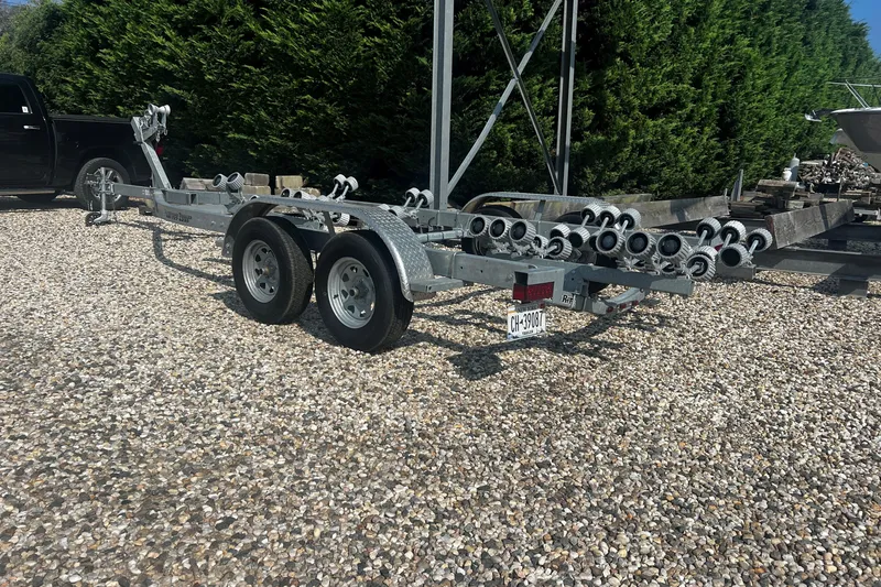 Slide: The Image of Trailer for 2019 Key West 239 FS boat on gravel lot, surrounded by greenery. - 17