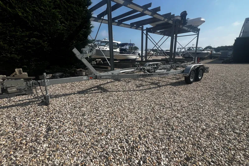 Slide: The Image of Trailer for 2019 Key West 239 FS boat on gravel lot with boats in background. - 16