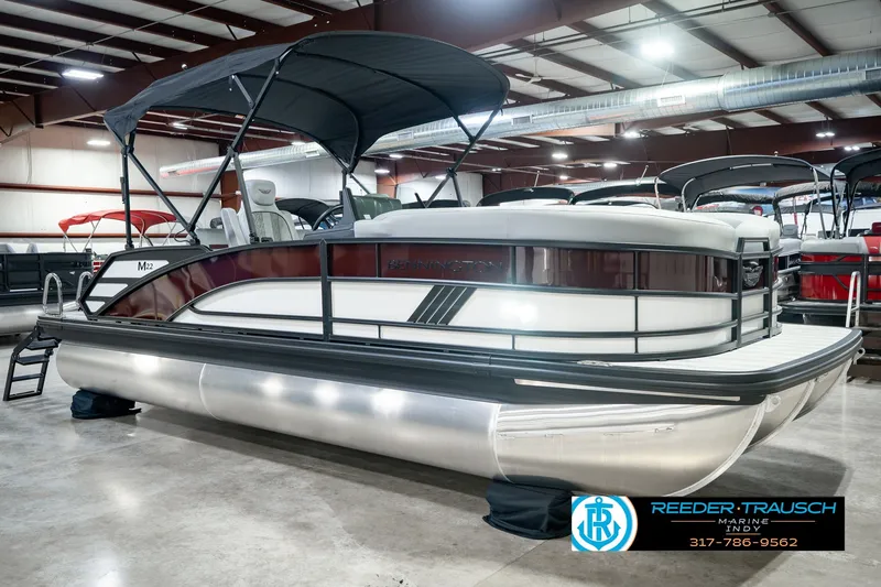 Slide: The Image of 2027 Bennington 22 MSB pontoon boat displayed indoors with canopy and sleek design. - 5
