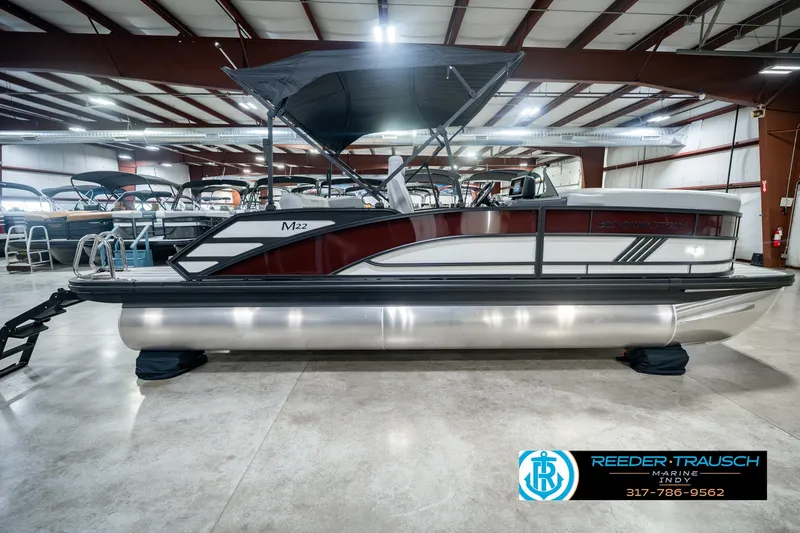 Slide: The Image of 2027 Bennington 22 MSB pontoon boat displayed indoors at Reeder-Trausch Marine showroom. - 6