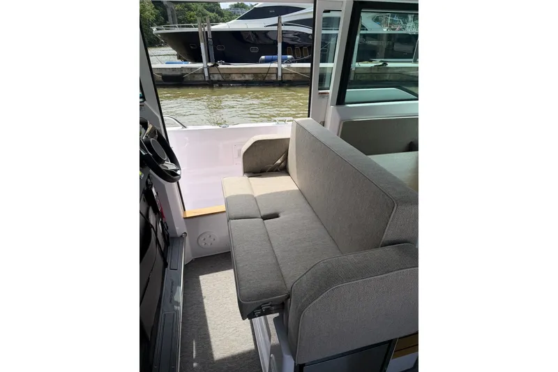 Slide: The Image of 2025 Axopar 37 XC Cross Cabin interior with gray seating, docked by the water. - 14