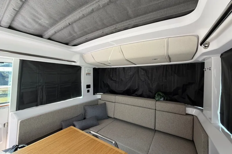 Slide: The Image of 2025 Axopar 37 XC Cross Cabin interior with gray seating and wooden table. - 15