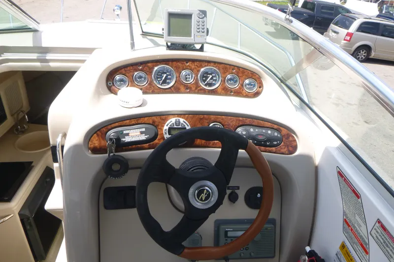Slide: The Image of 2002 Sea Ray Sundancer 260 helm with steering wheel, gauges, and navigation equipment. - 13